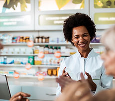 A pharmacist with a smile assists an elderly couple with their purchase.