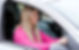 A woman with long blonde hair is seated in the driver’s seat of a car