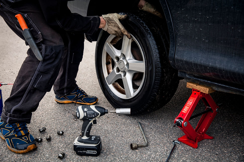 A mechanic changing car tyre on the side of the road
