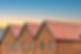 Row of modern red brick houses with pitched terracotta tiled roofs at sunset