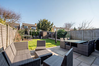 A small back garden with a green lawn and wooden fencing