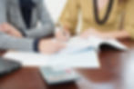 Professionals discussing paperwork on a desk with a calculator