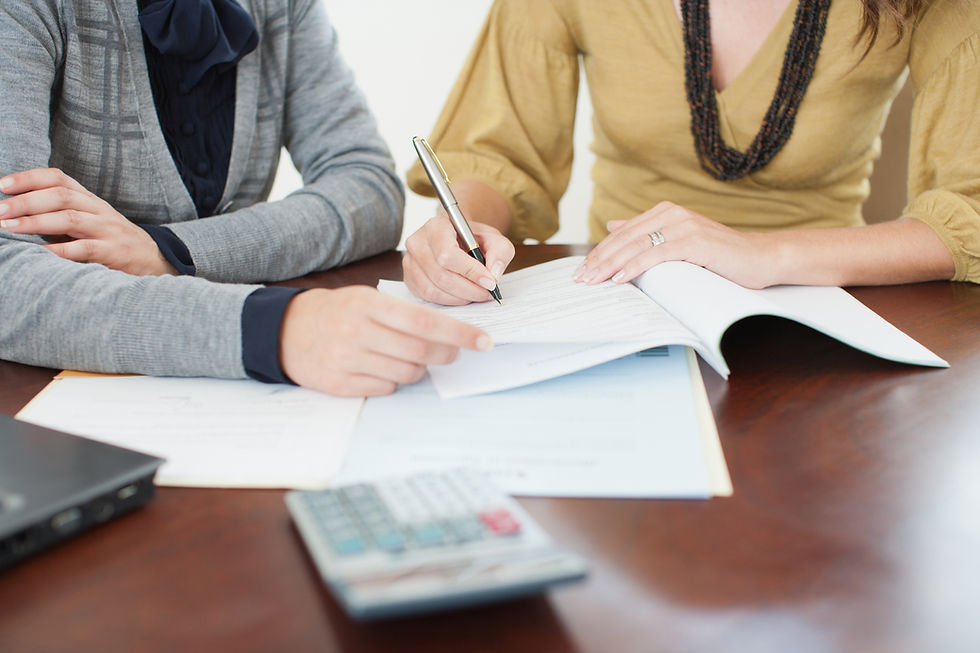 Close-up of client signing contract during consultation with professional using calculator at desk