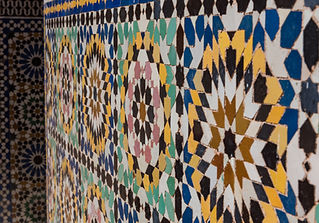 An intricate geometric Moroccan mosaic tile wall features colorful, repeating starburst patterns