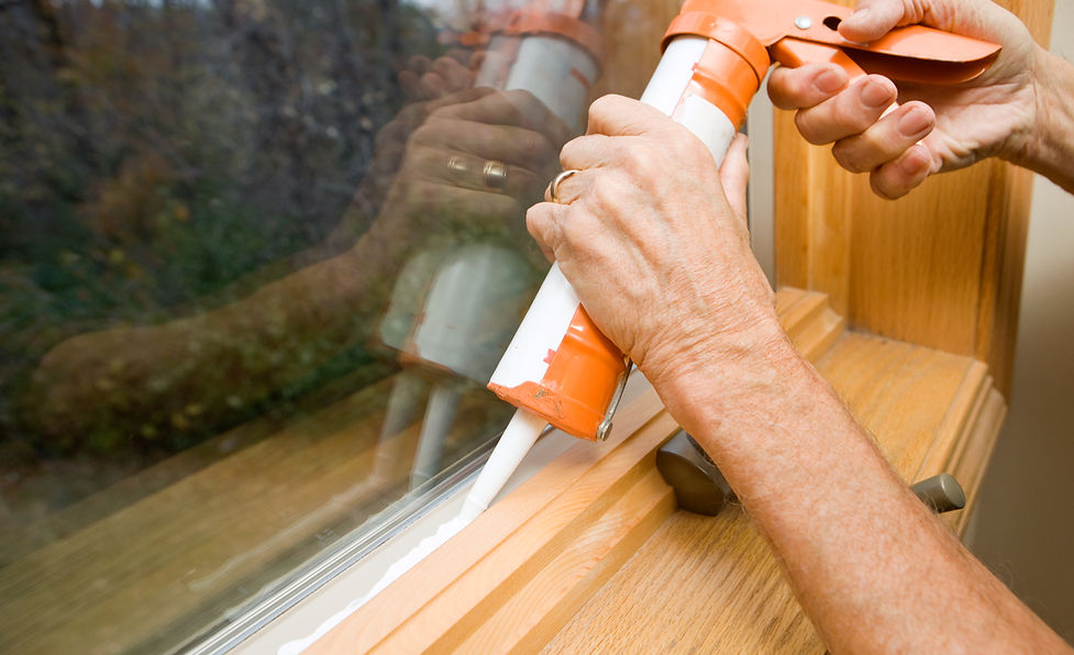 Close-up of hands applying weather seal caulk to window frame
