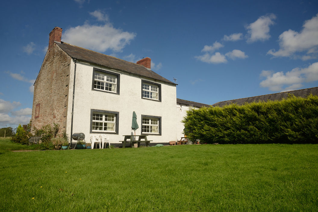 Country farm house with lawn and blue sky with clouds