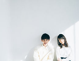 壁にもたれる白いシャツを着た男女