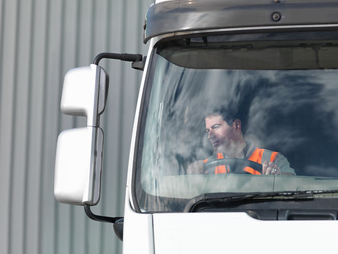 A man sits inside a truck, visible through the windshield