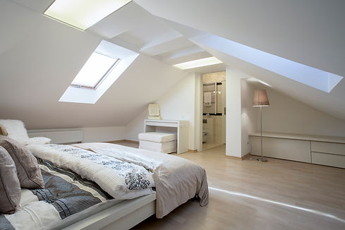 A modern attic bedroom with sloped ceilings, skylights, and soft lighting