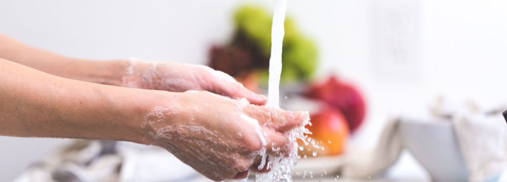 Washing hands in a kitchen sink for food safety.