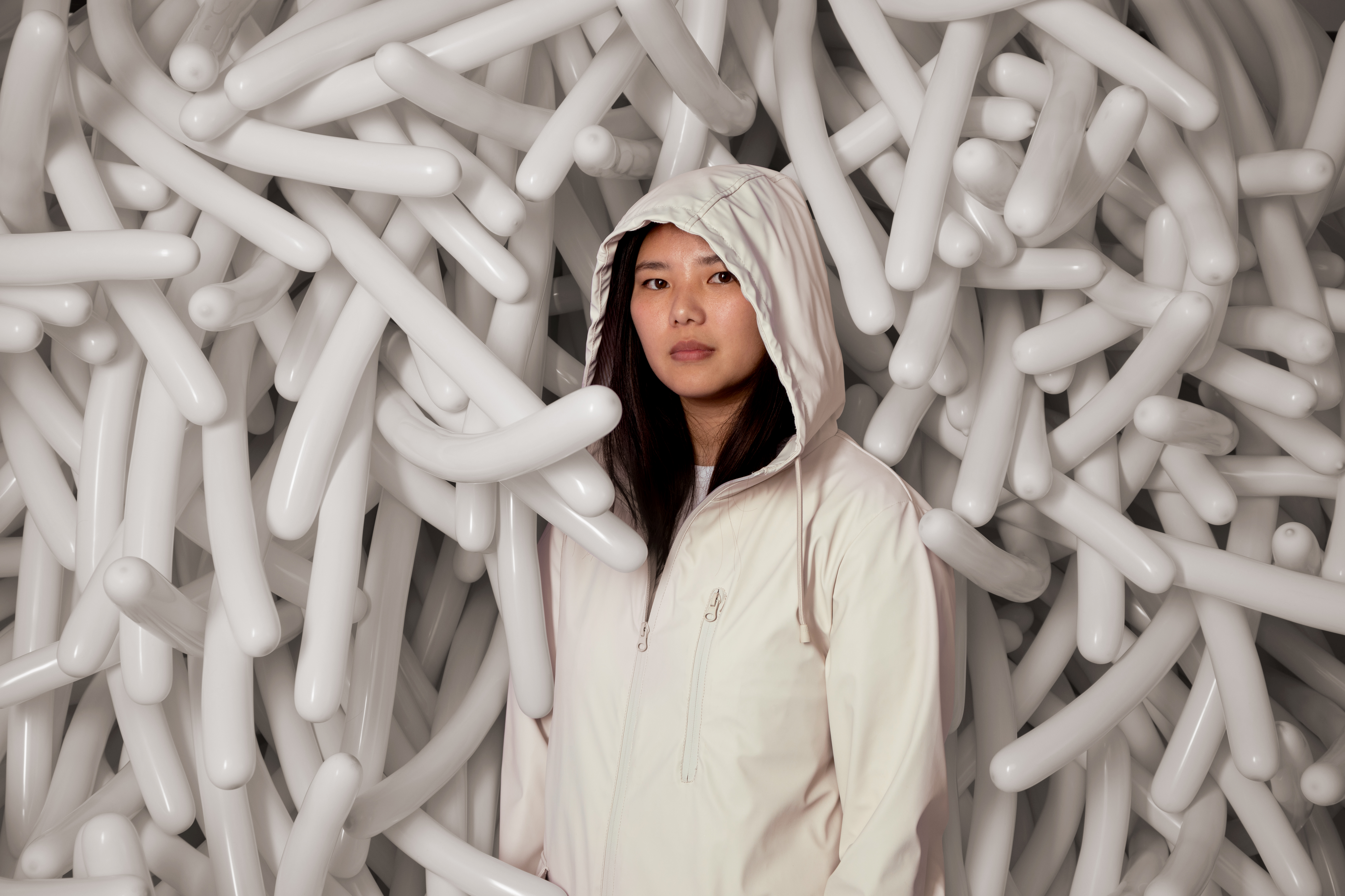 Woman in white jacket posing against background with white sticks.