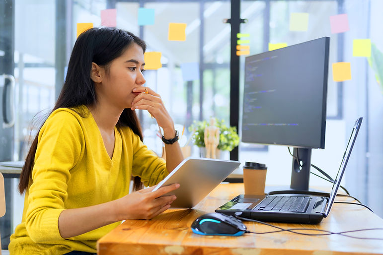 Una mujer pensando frente a las pantallas de los ordenadores