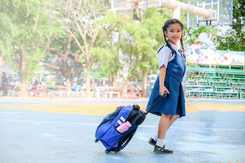 A child walking into an elementary school building on the first day of school, representing LEP families navigating a new school year.