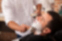 A barber shaving a young man's face