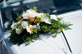 Floral arrangement of white roses and greenery on car hood