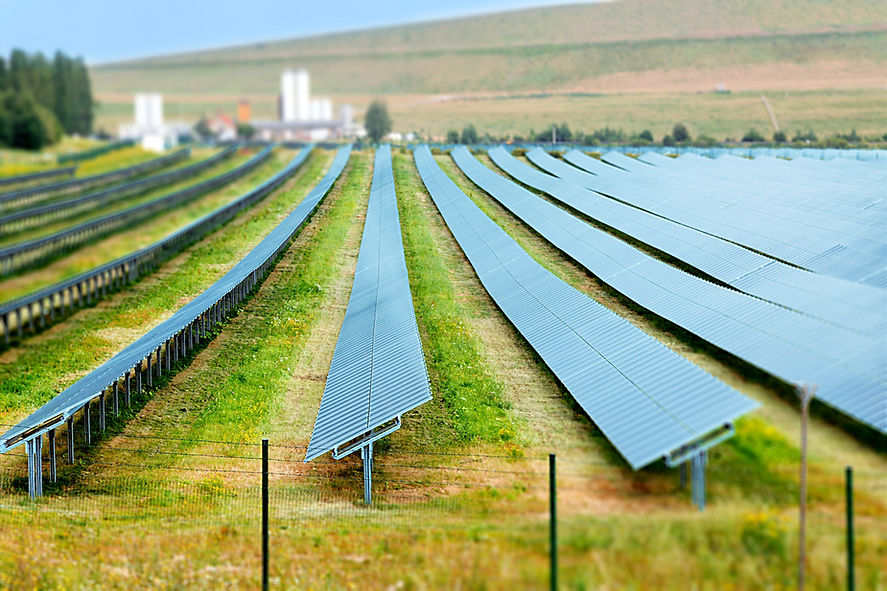 Tilt-shift image of a solar farm with rows of solar panels on grassy fields