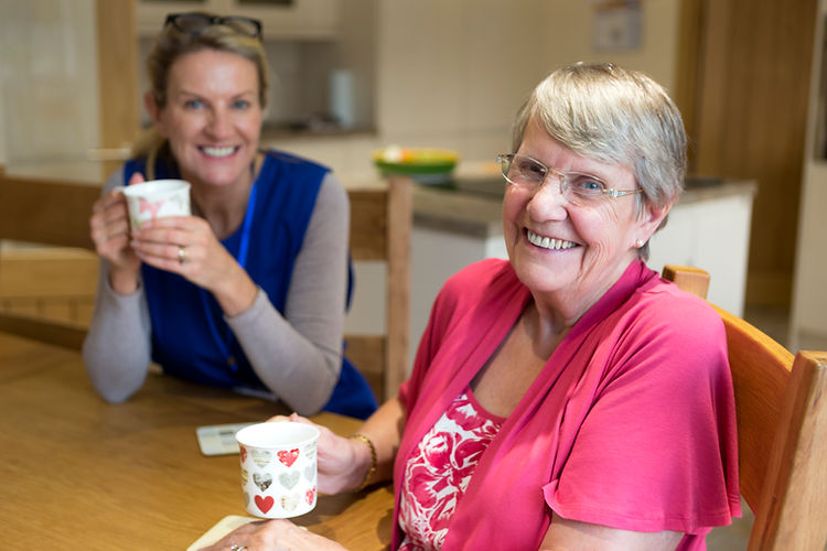 Community care worker joins an an elderly woman for a cup of tea