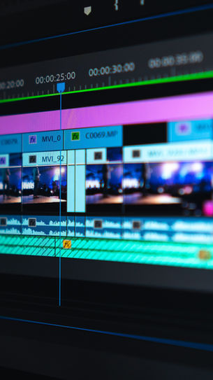 Close-up of a video editing timeline on a computer screen, showing colorful tracks and thumbnails. Timecodes are visible.