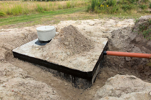 Concrete septic tank lid and riser emerging from a dirt pile