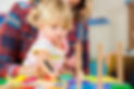 Sweet blonde preschooler colouring while sitting on her mother’s lap