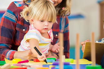 Sweet preschooler sitting on her mother's lap while coloring