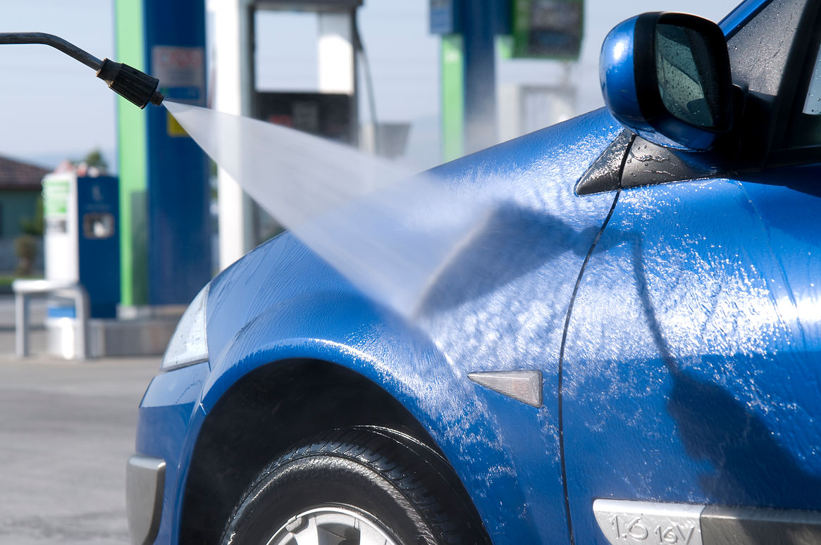 a person using high-pressure washer for cleaning blue car