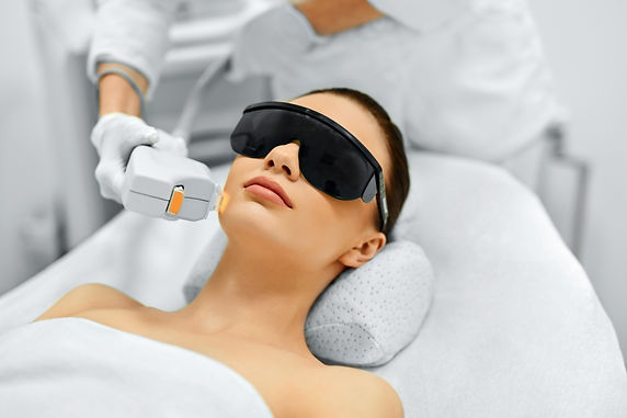 Woman wearing laser safety goggles receiving a facial laser treatment