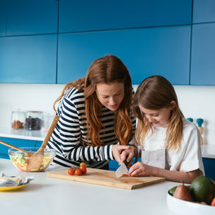 Kind steht mit Mutter in der Küche