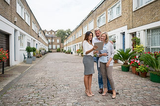 Realtor showing houses to a happy couple on her tablet computer - real estate concepts