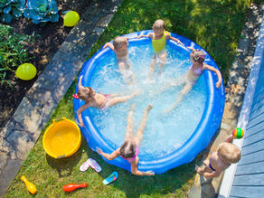 Six kids sitting in backyard inflatable pool