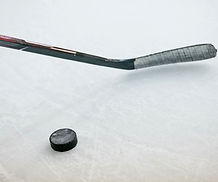 A hockey stick and puck symbolizing Trish Guise's expertise in risk analysis for sports, emphasizing proactive strategies for athlete protection and legal considerations.