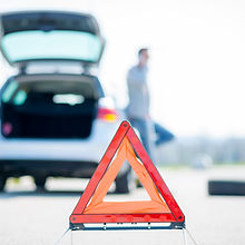 A young man with a silver car that broke down on the road
