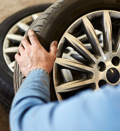 A mechanic examining the tyres of a car