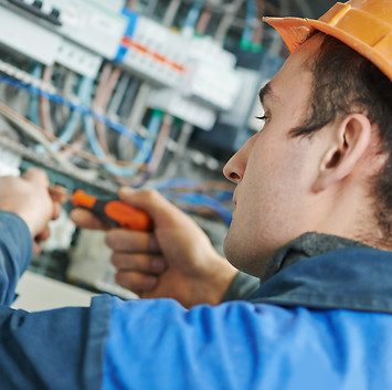 Young adult electrician builder engineer screwing equipment in fuse box