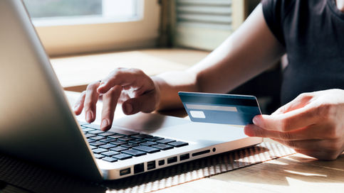 A close-up shot of a person using a laptop and holding a credit card to complete an online purchase, illustrating a cross-border digital presence and what most businesses overlook regarding international checkout systems.