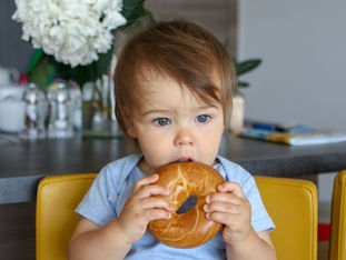 Baby eating a bagel by themslef