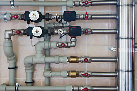 Complex heating system pipework with valves, gauges and pumps installed on a wall