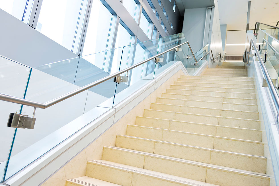 a modern architectural interior with a straight marble staircase, frameless tempered glass balustrade panels, and a sleek stainless steel handrail