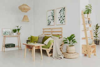 Modern, minimalist living room with a wooden sofa, green cushions, and framed leaf artwork on a white wall