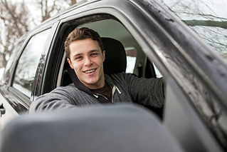 A man smiling sitting in the driver's seat of a car