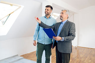 Two male estate agents in smart casual clothing discussing a floor plan layout