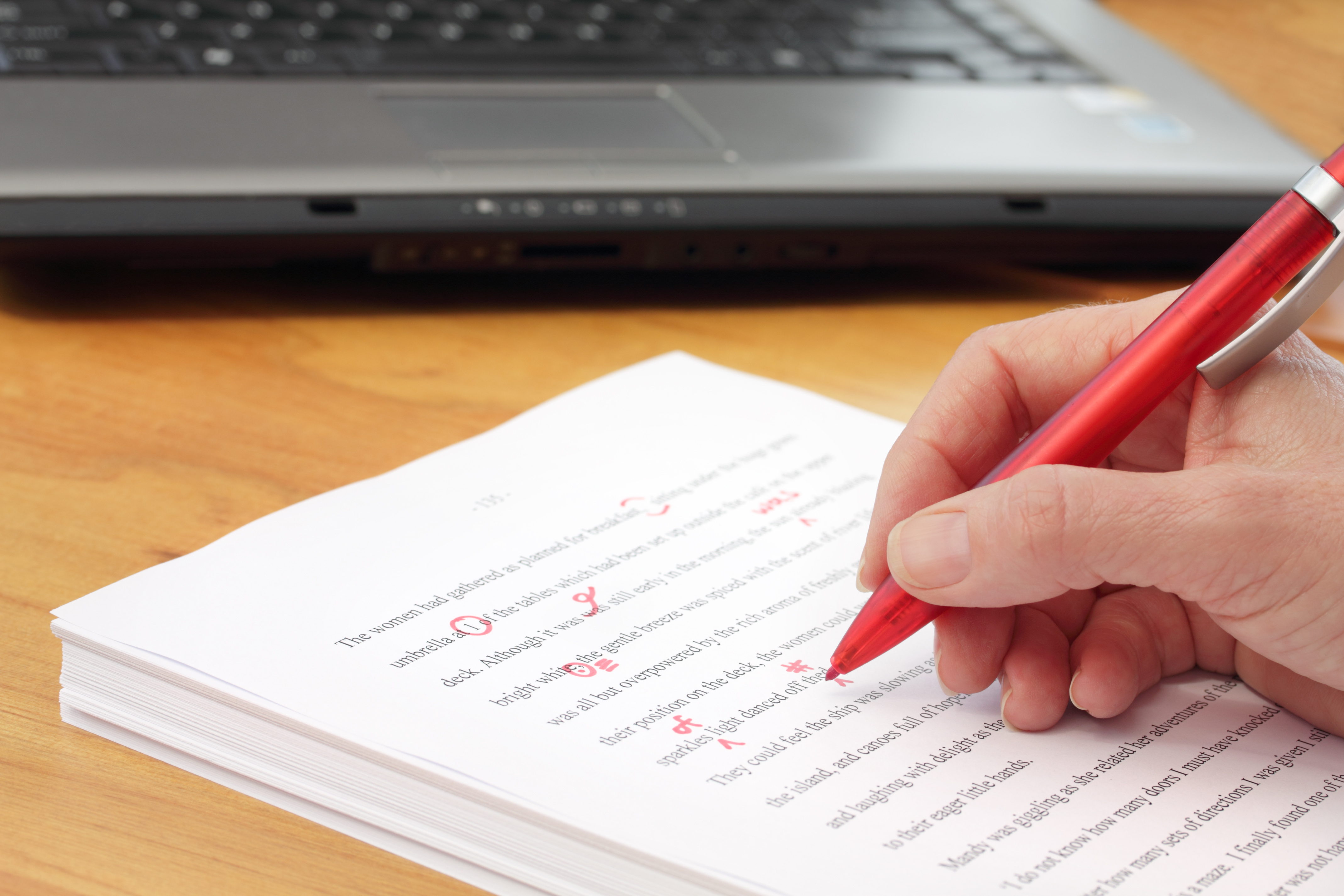 red pen making amendments to text in a stack of papers