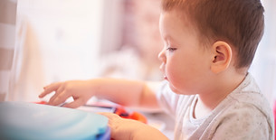Young child playing with a blue toy in a bright room