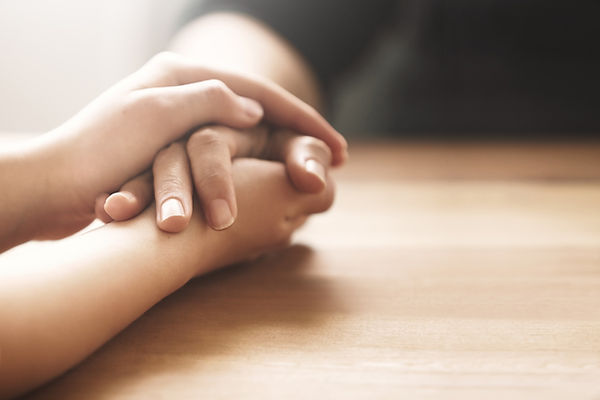 Detailed close up of hands holding one another gently to express deep sympathy and reassurance
