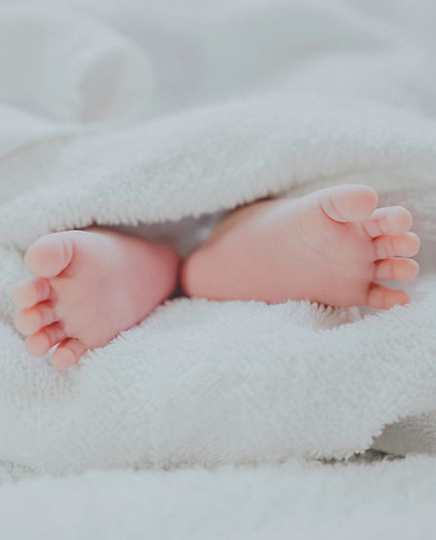 Baby feet resting on white towels after baby massage Baddesley Ensor