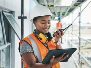 Site lead in a hard hat and safety vest checks the scaffold on a tablet — construction safety checklist