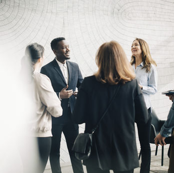 Group of business associates standing and talking, dressed in professional suits.