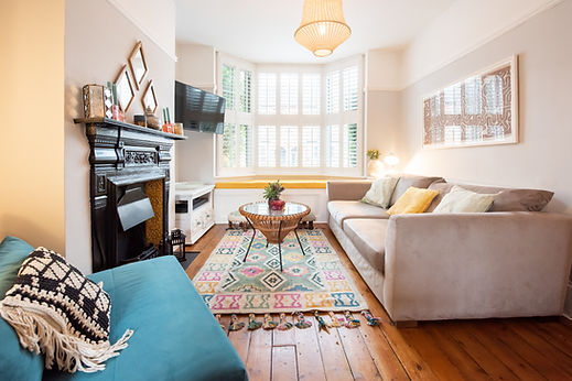 Sunlit living room featuring bay window shutters fireplace and stylish furniture