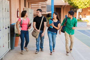 A group of teens walk by lockers in a high school