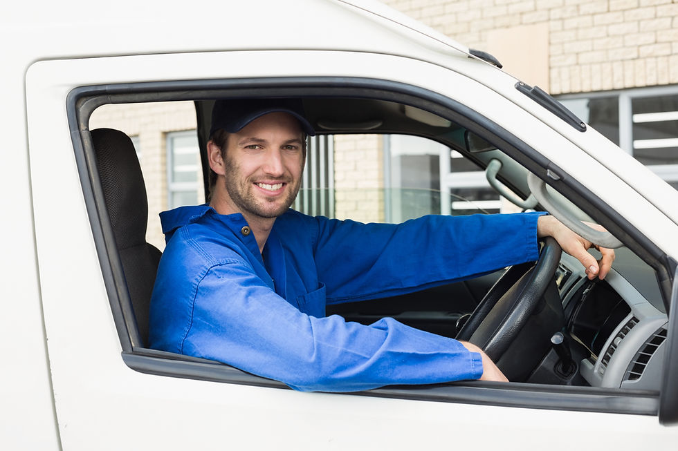 A smiling man driving a truck, showcasing a cheerful expression while focused on the road ahead